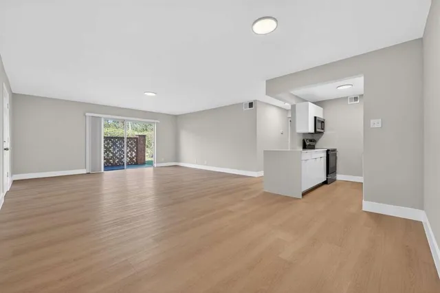 a view of empty room with wooden floor and window