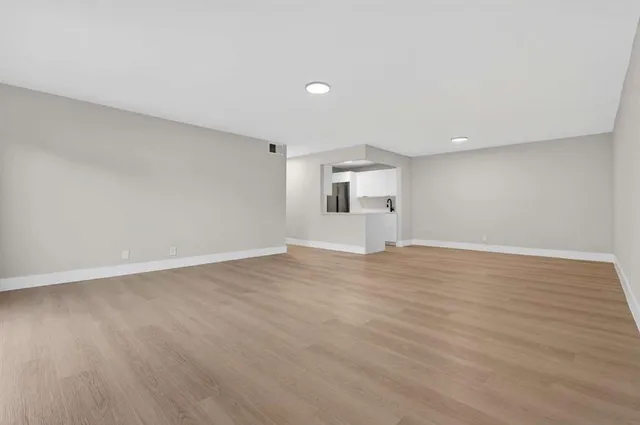 a view of empty room with wooden floor and window