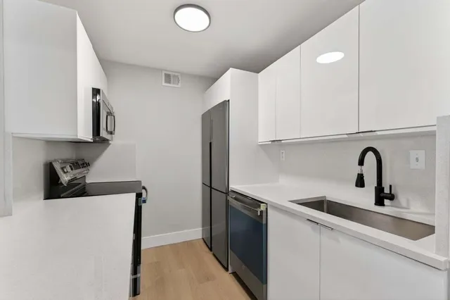a kitchen with stainless steel appliances a sink a refrigerator and cabinets