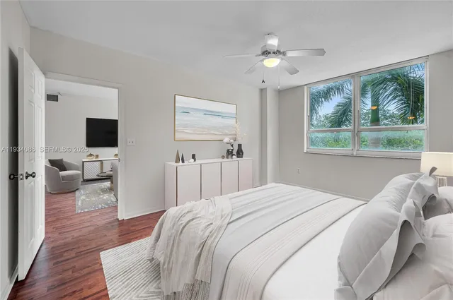 a bedroom with a large bed a flat tv screen and a large window