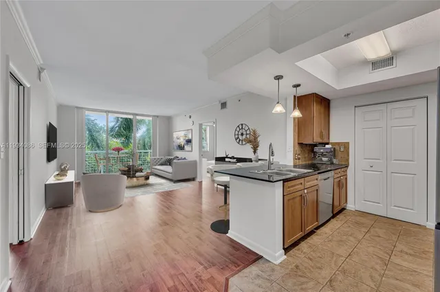 a kitchen with stainless steel appliances granite countertop a stove and a view of living room