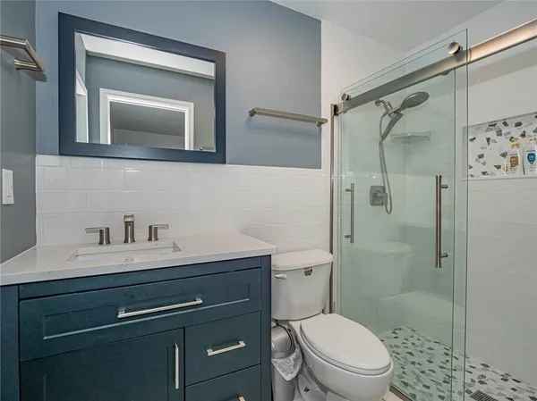 a bathroom with a toilet a sink a vanity and shower