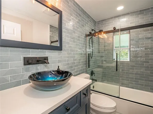 a bathroom with a sink a toilet a mirror and shower