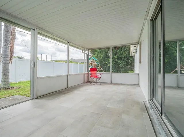 a view of an empty room with wooden floor and windows