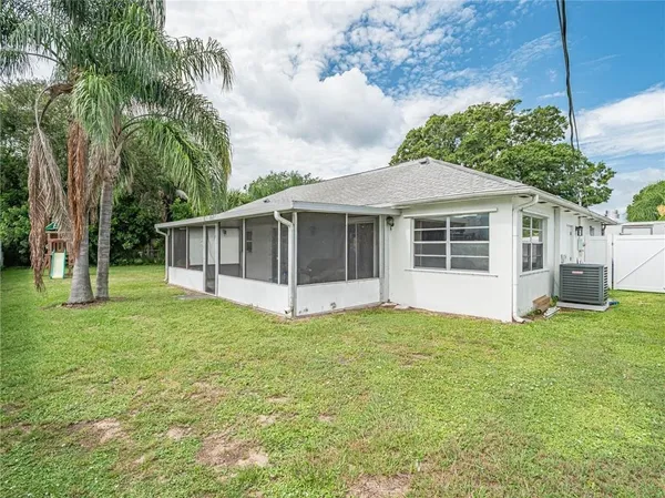 a white house with a small yard and large trees