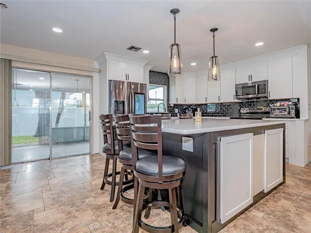 a kitchen with stainless steel appliances granite countertop a stove a refrigerator a sink a dining table and chairs with wooden floor