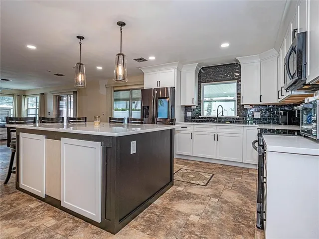 a kitchen with stainless steel appliances granite countertop a sink a stove and a refrigerator