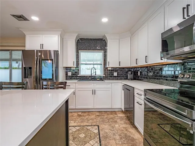 a kitchen with stainless steel appliances granite countertop a stove a sink and a microwave