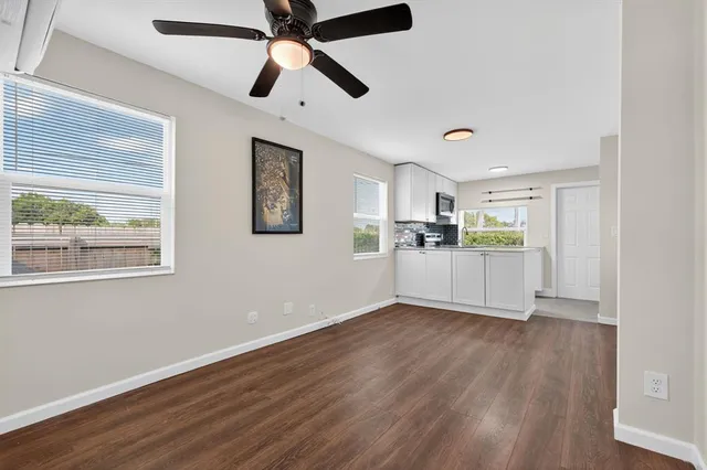 a view of a kitchen with wooden floor a ceiling fan and windows