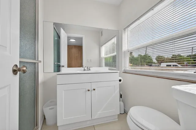 a bathroom with a sink a toilet a mirror and window