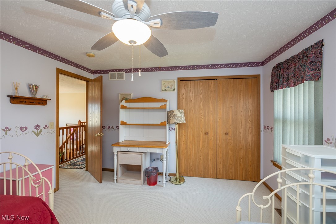 12181 Williams Road Homerville, OH 44235 - Photo 24 of 49 Bedroom with a closet, ceiling fan, a textured ceiling, and light colored carpet
