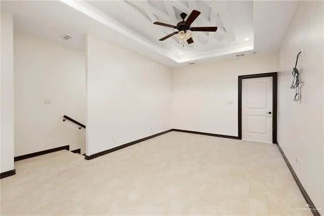 an empty room with a ceiling fan and wooden floor