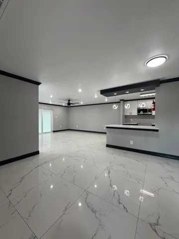 a large white kitchen with stainless steel appliances a large counter top a stove and a sink