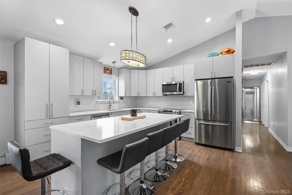 a kitchen with stainless steel appliances granite countertop a sink a stove a refrigerator and island with wooden floor