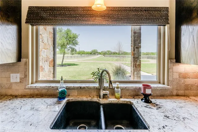 a kitchen with a sink a counter top space and a view of living room