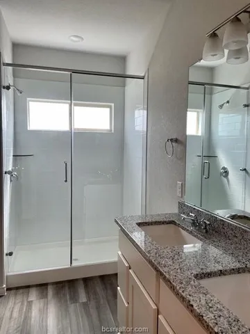 a bathroom with a granite countertop sink mirror and shower