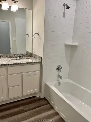 a bathroom with a granite countertop sink and a bathtub