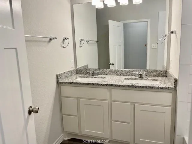a bathroom with a granite countertop sink and a mirror