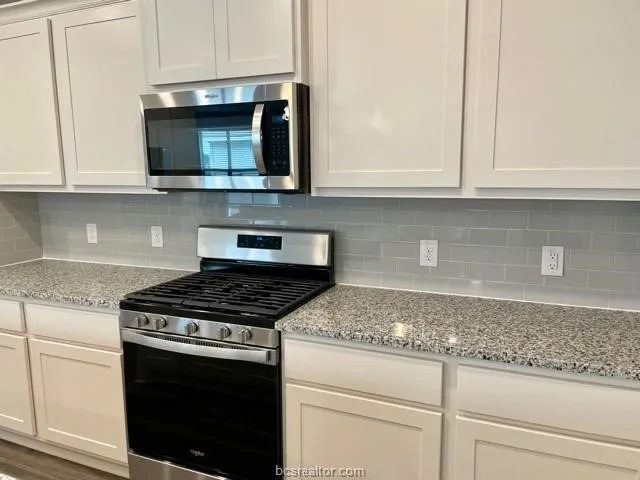 a kitchen with stainless steel appliances granite countertop white cabinets and a stove