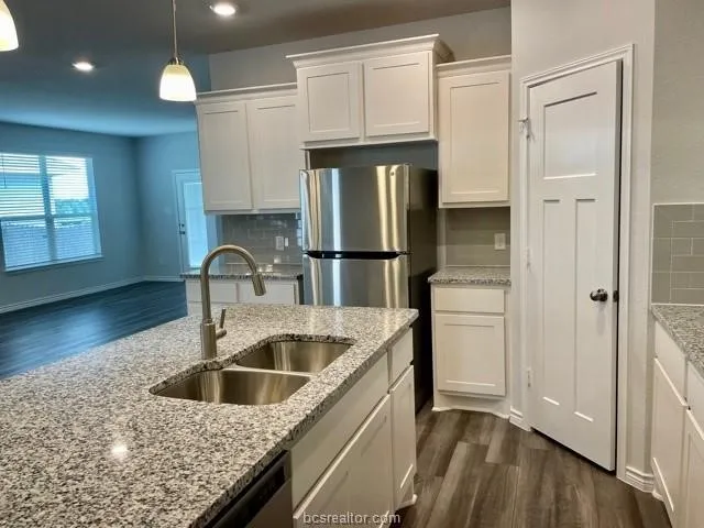 a kitchen with kitchen island granite countertop a sink stainless steel appliances and cabinets
