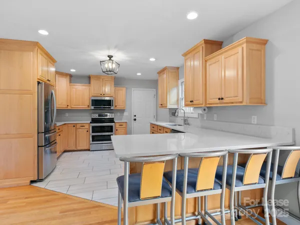 a kitchen with granite countertop a table chairs microwave and refrigerator