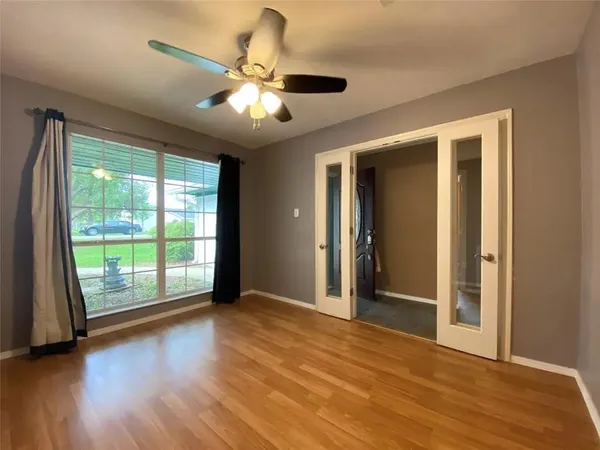 an empty room with window and ceiling fan