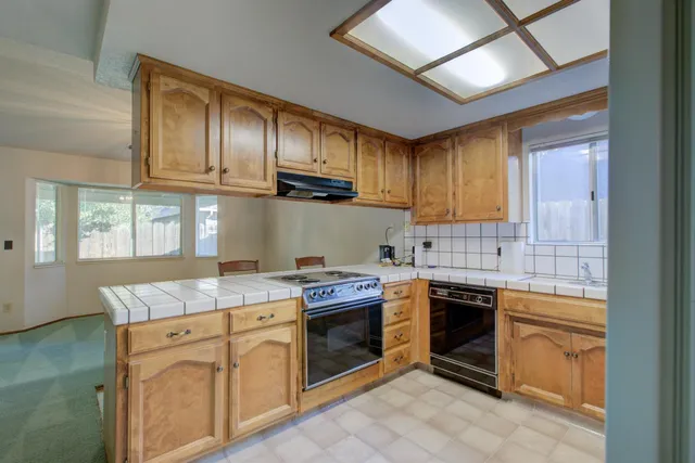 a kitchen with granite countertop stainless steel appliances a stove sink and cabinets