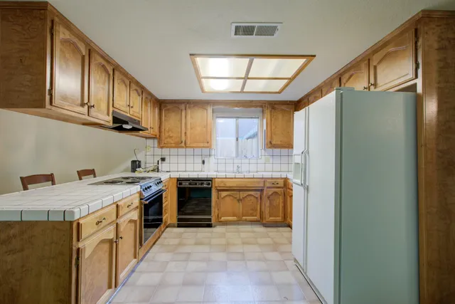 a kitchen that has a lot of cabinets in it and stainless steel appliances