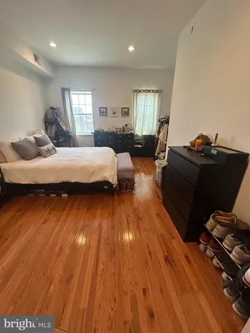 a spacious bedroom with a bed and wooden floor