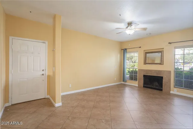 an empty room with windows fireplace and fan