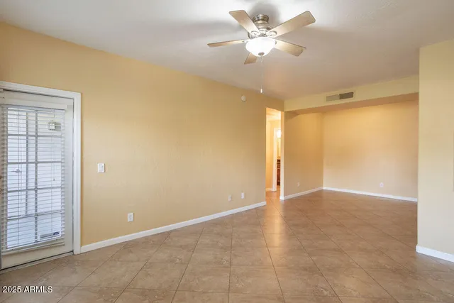 an empty room with windows and fan