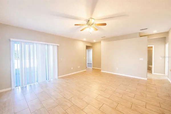 a view of an empty room with chandelier fan and a window