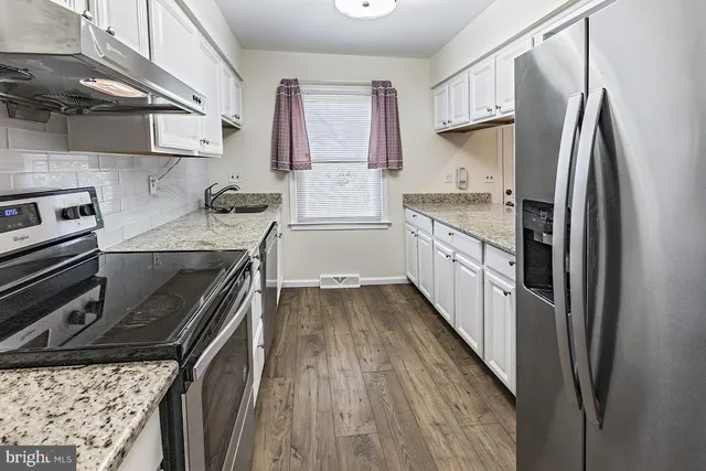 a kitchen with granite countertop a refrigerator stove and sink