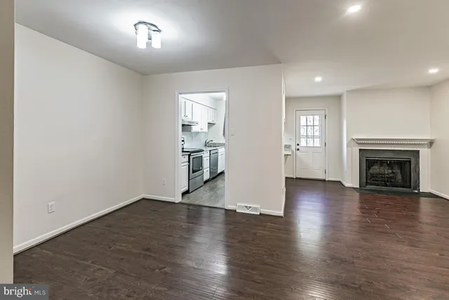 an empty room with wooden floor fireplace and windows