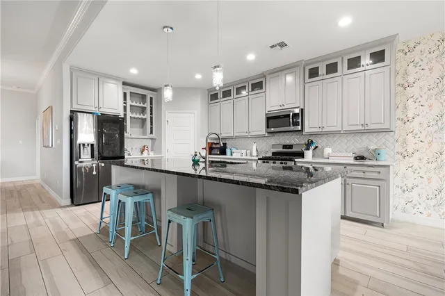 a kitchen with granite countertop a refrigerator stove microwave and cabinets