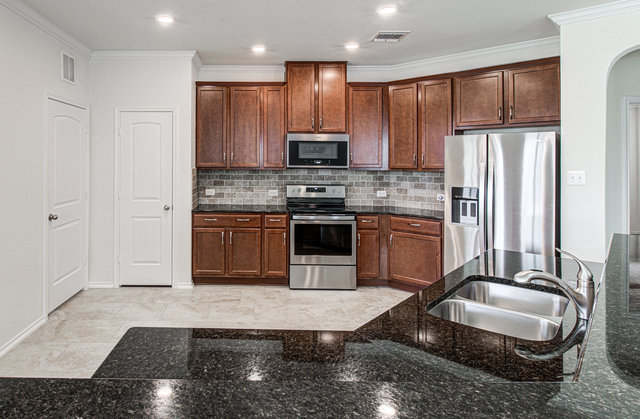 1237 Volente Lane Leander, TX 78641 - Photo 5 of 22 A well-appointed kitchen features rich wood cabinetry, stainless steel appliances, and gleaming black granite countertops.