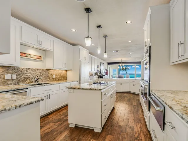 a kitchen with stainless steel appliances granite countertop a lot of counter space and wooden floors