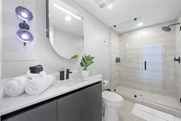 a bathroom with a granite countertop sink mirror toilet and shower