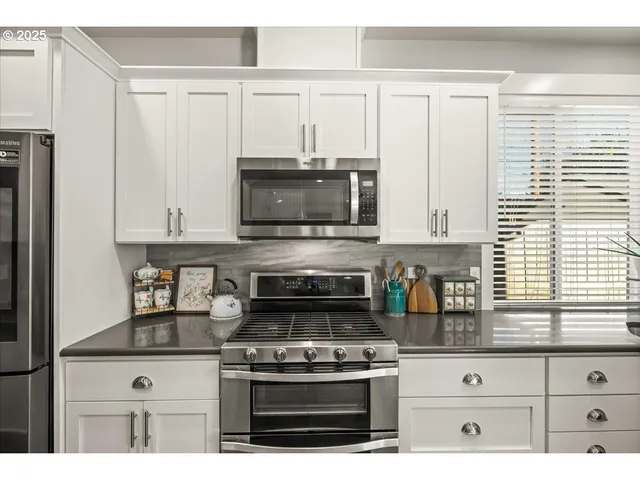 a kitchen with granite countertop a stove oven and white cabinets
