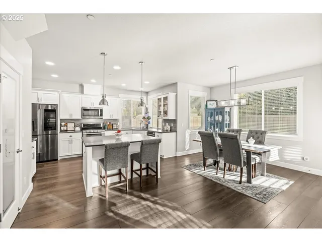 a dining room with stainless steel appliances kitchen island granite countertop a dining table chairs and granite counter tops