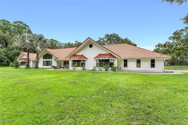 a view of a white house with a big yard and large trees