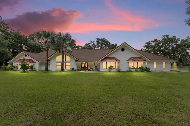 a view of a big house with a big yard and large trees