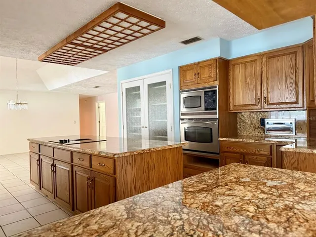 a kitchen with stainless steel appliances kitchen island granite countertop a refrigerator stove and sink