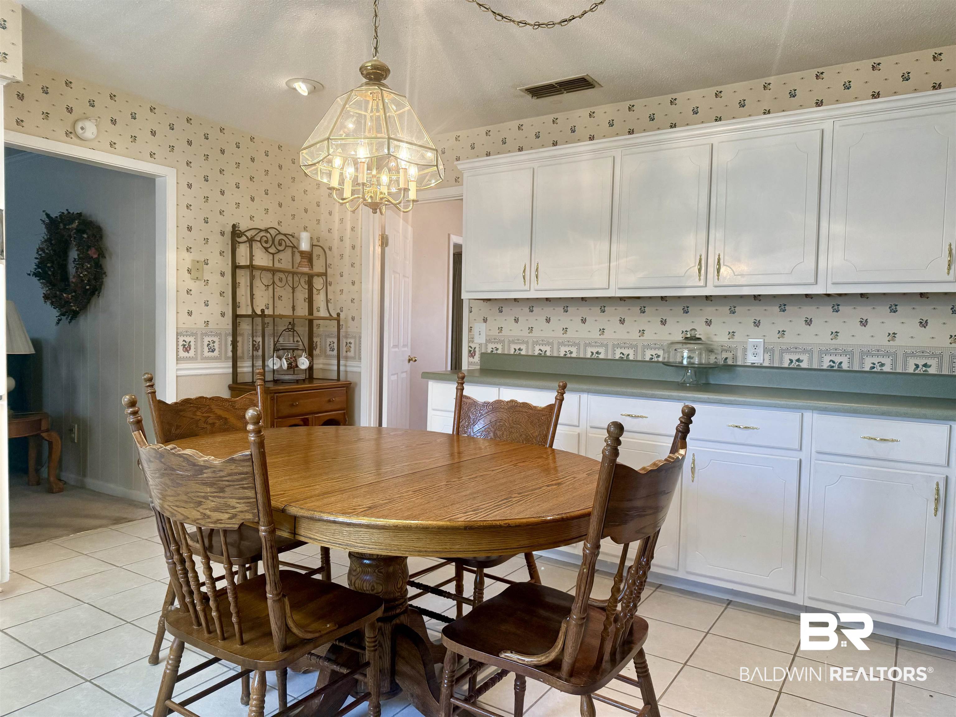 215 Young Street Brewton, AL 36426 - Photo 6 of 25 Dining room featuring light tile patterned flooring, a chandelier, a wainscoted wall, and wallpapered walls