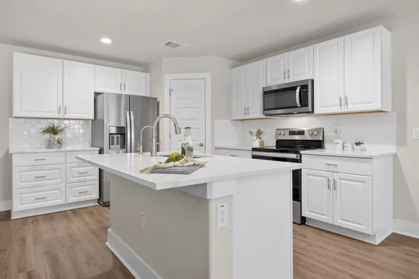 a kitchen with stainless steel appliances granite countertop a table chairs and a refrigerator