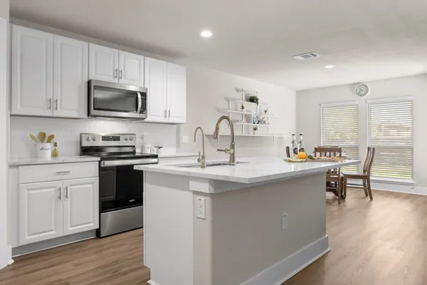 a kitchen with stainless steel appliances granite countertop a sink stove and wooden floor