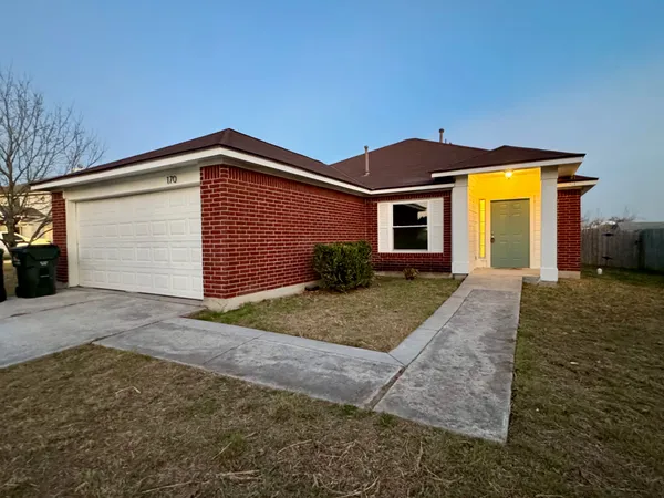 a front view of house with yard and trees in the background