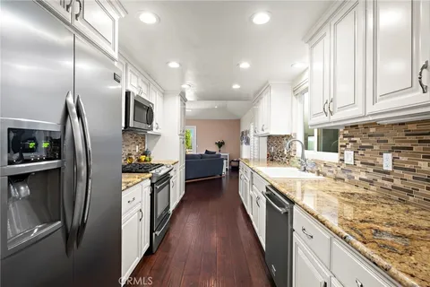 a large kitchen with granite countertop a large counter top appliances and cabinets