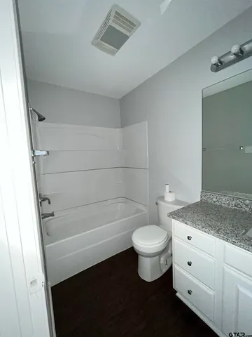 a bathroom with a granite countertop sink a toilet and bathtub