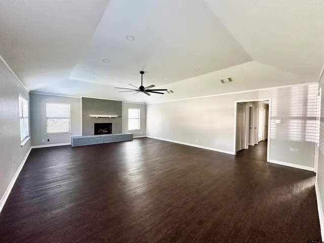 an empty room with wooden floor fireplace and windows